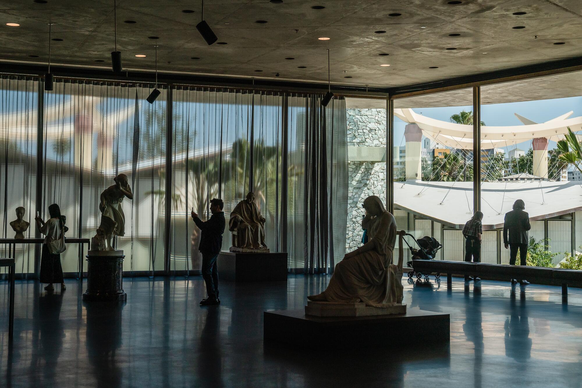 A sculpture in a museum with floor-to-ceiling windows.