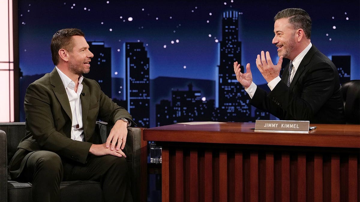 Eric Swalwell and Jimmy Kimmel stand together in front of the television.